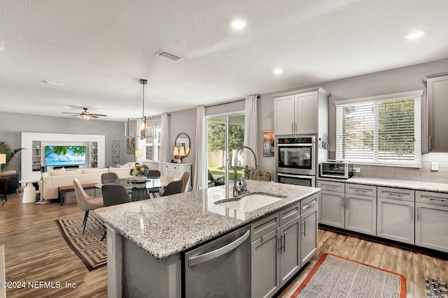 kitchen with a wealth of natural light, appliances with stainless steel finishes, a kitchen island with sink, and sink