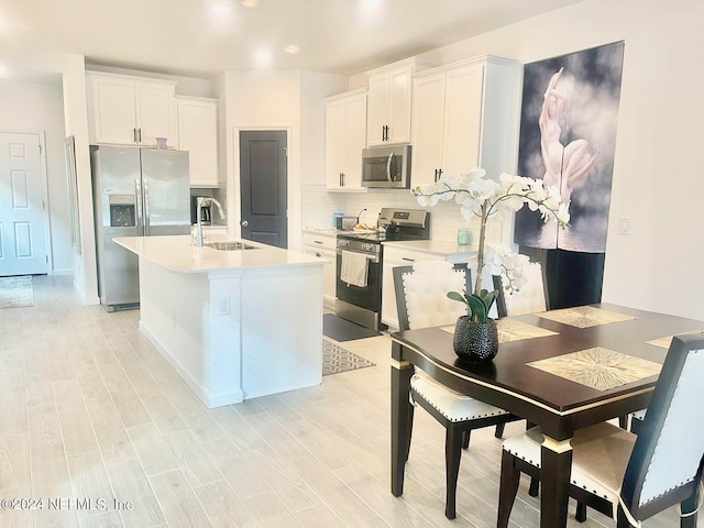 kitchen with white cabinets, sink, light hardwood / wood-style flooring, tasteful backsplash, and stainless steel appliances