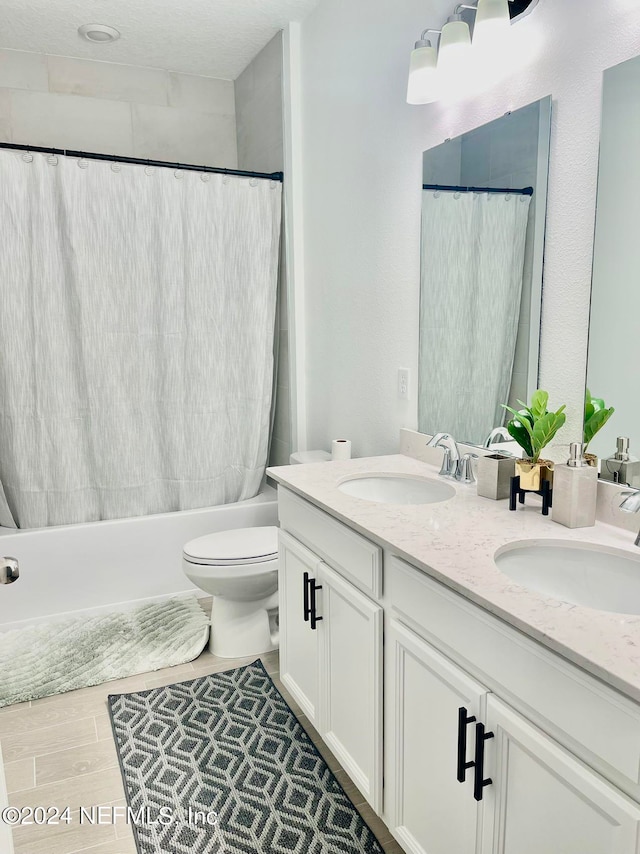 full bathroom featuring shower / bath combination with curtain, wood-type flooring, a textured ceiling, toilet, and vanity