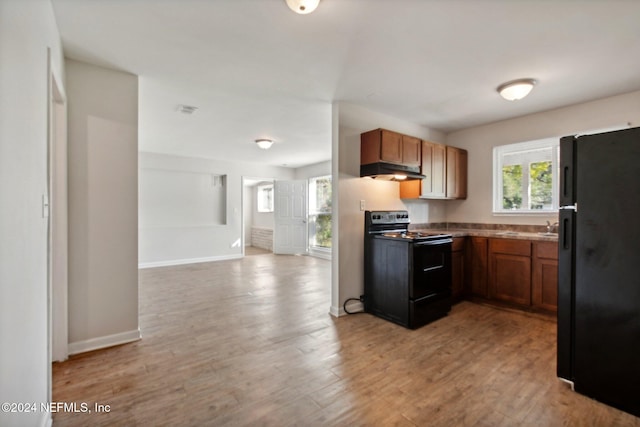 kitchen featuring black appliances, sink, and light hardwood / wood-style flooring