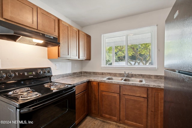 kitchen featuring black electric range, light hardwood / wood-style floors, sink, and stainless steel fridge