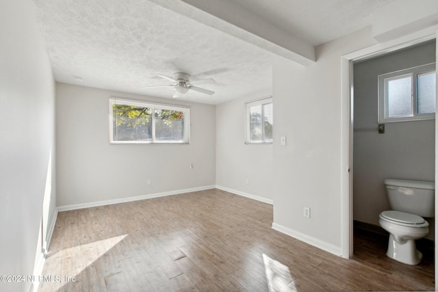 interior space featuring a textured ceiling, wood-type flooring, ceiling fan, and ensuite bath