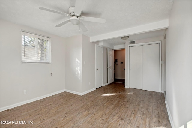 unfurnished bedroom featuring a closet, light wood-type flooring, a textured ceiling, and ceiling fan