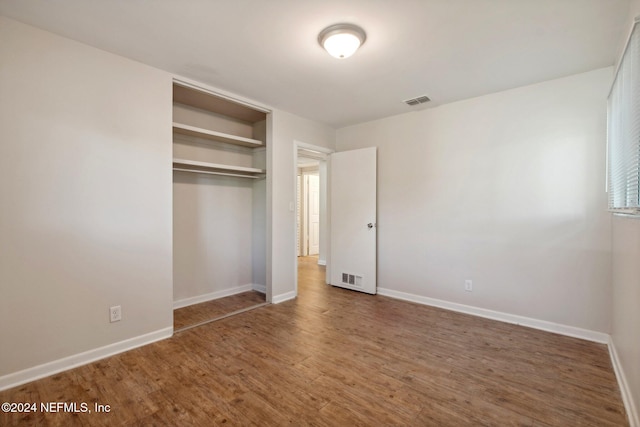 unfurnished bedroom with dark hardwood / wood-style floors and a closet