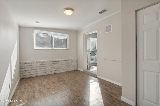 empty room with ornamental molding and hardwood / wood-style flooring