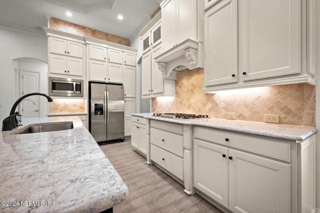 kitchen featuring sink, light wood-type flooring, white cabinetry, stainless steel appliances, and decorative backsplash