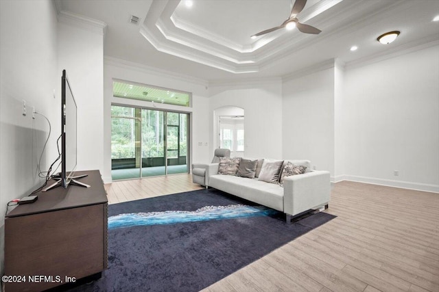 living room featuring hardwood / wood-style floors, a raised ceiling, crown molding, and ceiling fan