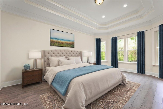 bedroom featuring ornamental molding, wood-type flooring, and a tray ceiling