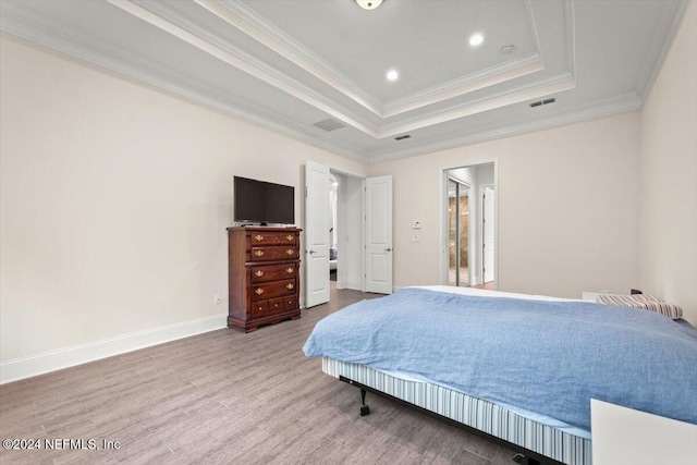 bedroom featuring ornamental molding, hardwood / wood-style flooring, and a tray ceiling