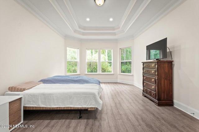 bedroom with ornamental molding, a tray ceiling, and wood-type flooring