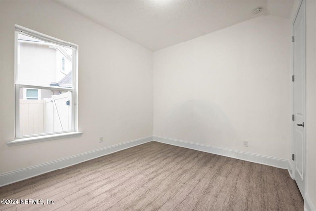 spare room with light hardwood / wood-style floors and lofted ceiling