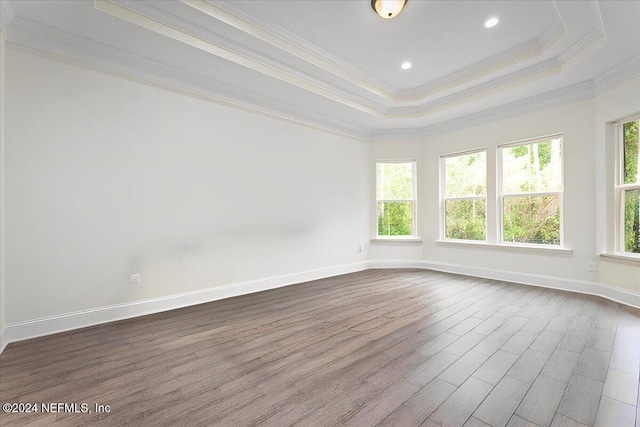 unfurnished room with ornamental molding, a tray ceiling, and wood-type flooring