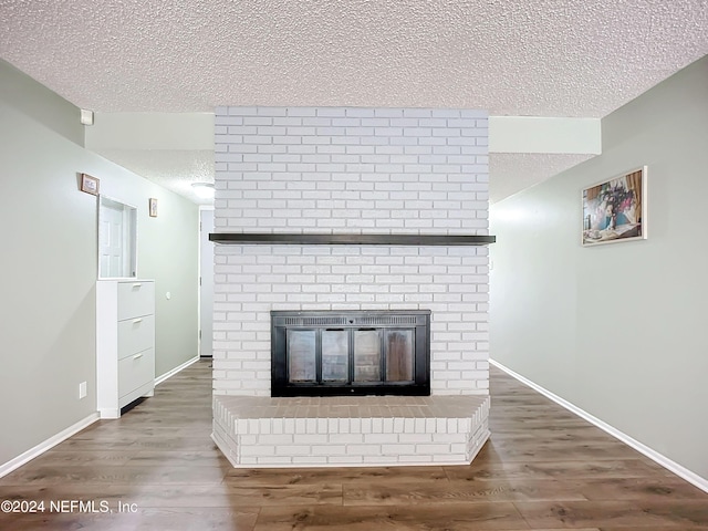 interior details featuring a textured ceiling, a brick fireplace, and wood-type flooring