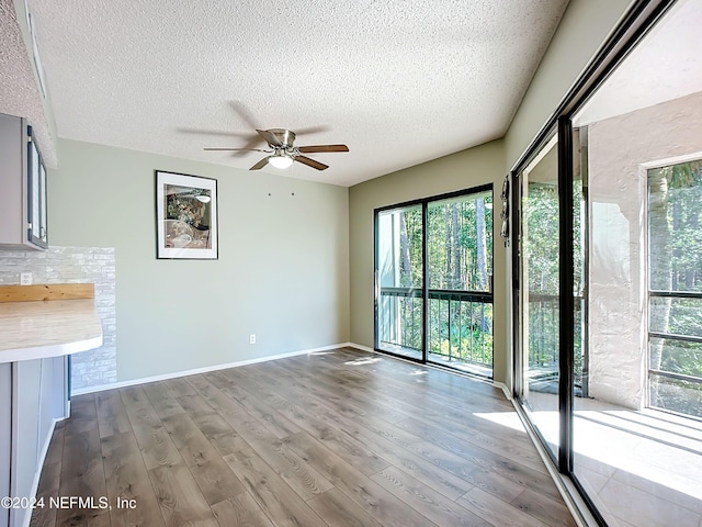 unfurnished living room with ceiling fan, hardwood / wood-style flooring, and a textured ceiling