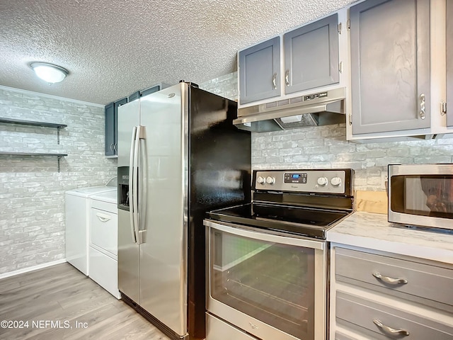 kitchen with washer and dryer, appliances with stainless steel finishes, a textured ceiling, light hardwood / wood-style floors, and gray cabinets