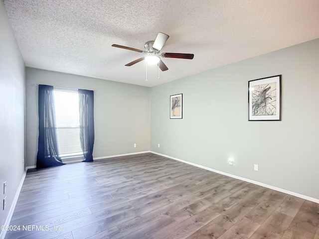 empty room featuring a textured ceiling, wood-type flooring, and ceiling fan