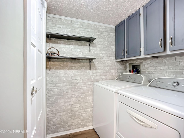 clothes washing area featuring cabinets, dark hardwood / wood-style flooring, a textured ceiling, separate washer and dryer, and brick wall