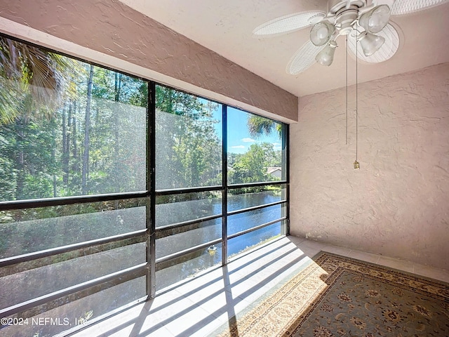 unfurnished sunroom featuring a water view and ceiling fan