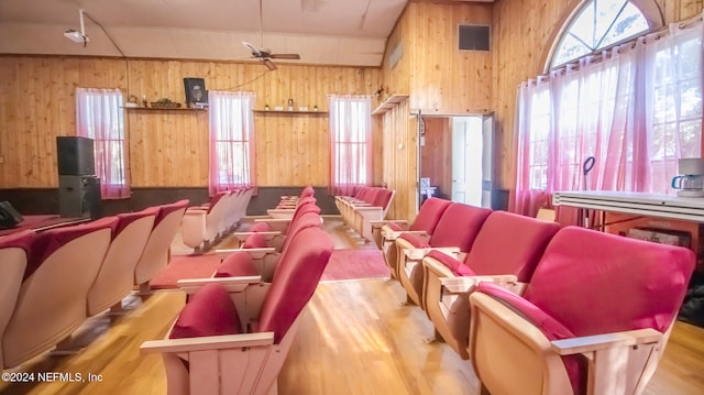 cinema featuring wood walls, high vaulted ceiling, light wood-type flooring, and ceiling fan