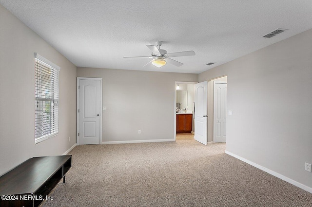 unfurnished bedroom featuring ceiling fan, a textured ceiling, and light colored carpet