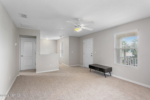 carpeted spare room featuring a textured ceiling and ceiling fan