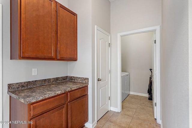 interior space featuring light tile patterned floors, washer and clothes dryer, and dark stone counters