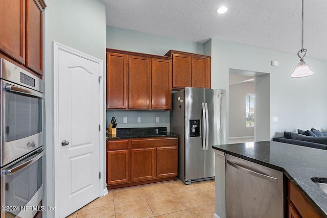 kitchen featuring hanging light fixtures, stainless steel appliances, dark stone countertops, light tile patterned floors, and a textured ceiling