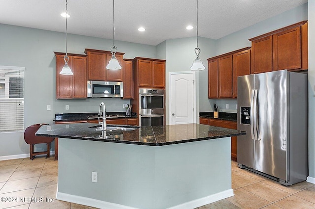 kitchen featuring stainless steel appliances, a textured ceiling, decorative light fixtures, and a kitchen island with sink