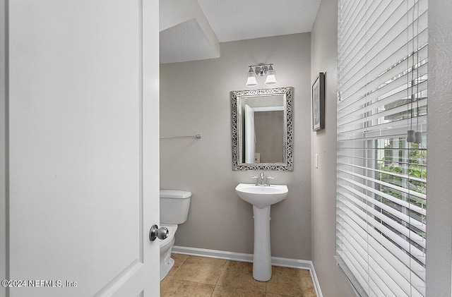 bathroom with toilet, a textured ceiling, and tile patterned flooring