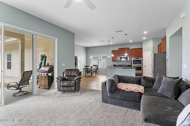 living room featuring a textured ceiling, light colored carpet, and ceiling fan