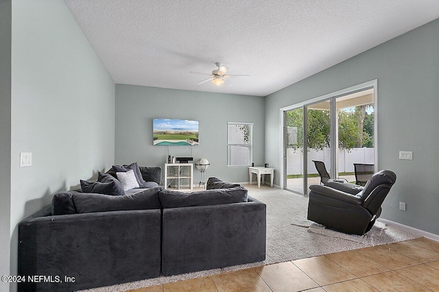 living room with ceiling fan, a textured ceiling, and light tile patterned floors