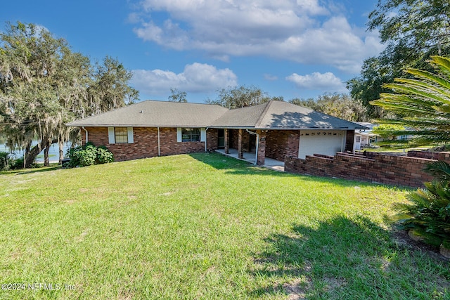 back of property with a garage, a water view, and a lawn