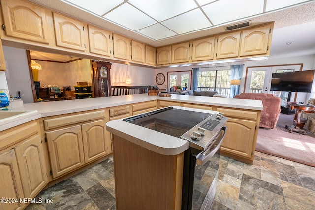 kitchen with light brown cabinetry, a kitchen island, kitchen peninsula, and electric stove