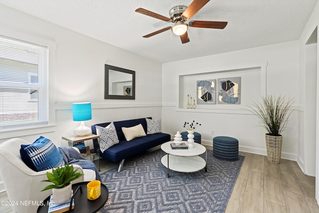 living room featuring a textured ceiling, wood-type flooring, and ceiling fan