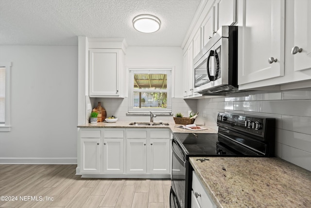 kitchen with white cabinets, electric range, light stone countertops, light wood-type flooring, and sink