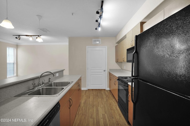 kitchen featuring hanging light fixtures, ornamental molding, sink, black appliances, and light hardwood / wood-style floors