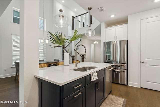 kitchen featuring light stone countertops, sink, dark hardwood / wood-style flooring, hanging light fixtures, and stainless steel appliances