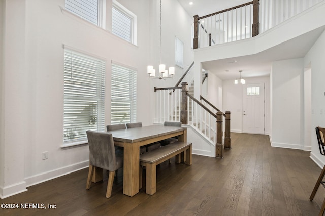 dining space featuring a towering ceiling, a notable chandelier, and dark hardwood / wood-style flooring