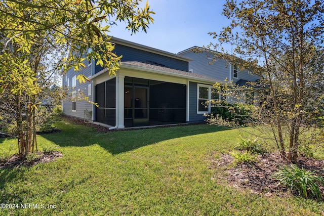 rear view of property with a lawn and a sunroom