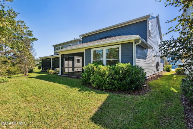 rear view of house with a lawn and a sunroom