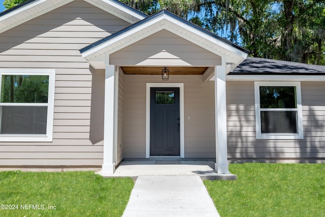 view of exterior entry featuring a lawn