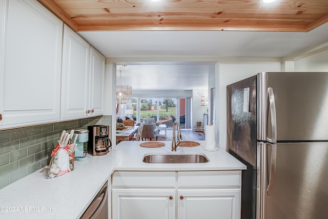 kitchen with sink, white cabinets, a chandelier, appliances with stainless steel finishes, and tasteful backsplash