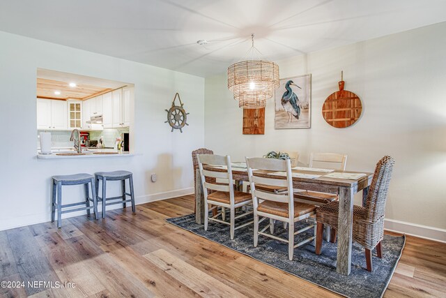 dining space with sink, a notable chandelier, and light hardwood / wood-style floors