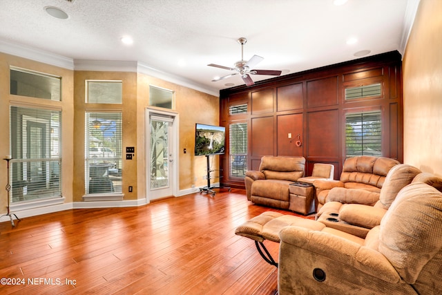 living room with crown molding, a textured ceiling, light hardwood / wood-style floors, and ceiling fan