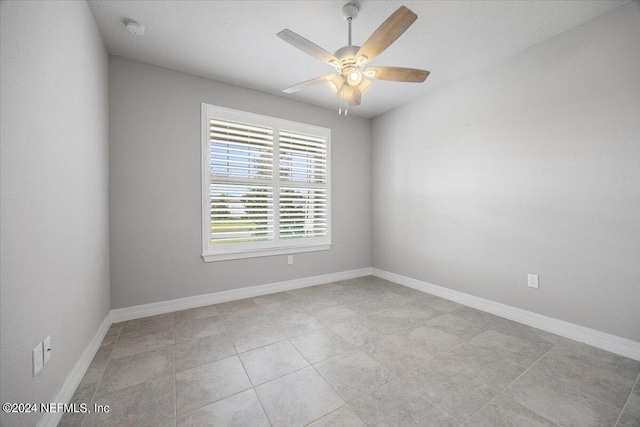 tiled spare room featuring ceiling fan