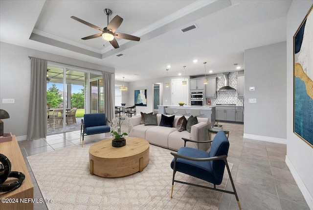 living room featuring ornamental molding, ceiling fan, light tile patterned floors, and a raised ceiling