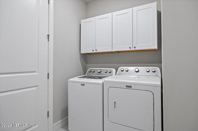 clothes washing area featuring washing machine and dryer and cabinets