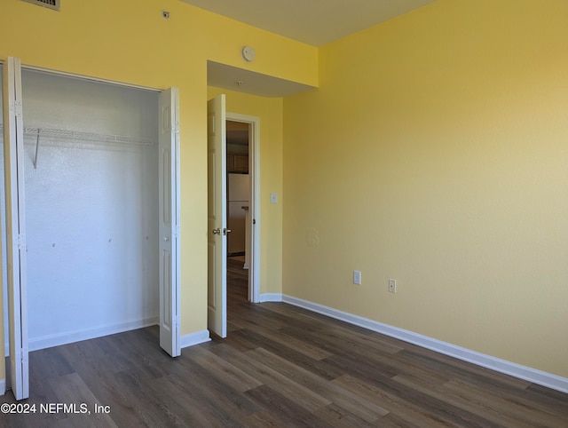 unfurnished bedroom featuring a closet and dark hardwood / wood-style flooring