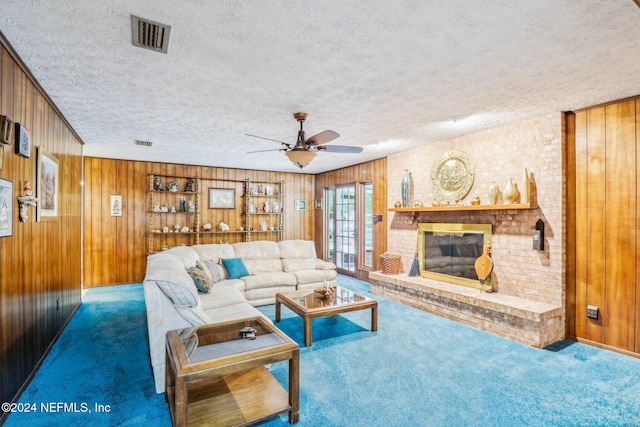 living room featuring wood walls, a fireplace, a textured ceiling, and carpet floors