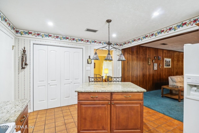 kitchen with a textured ceiling, light carpet, decorative light fixtures, and a center island